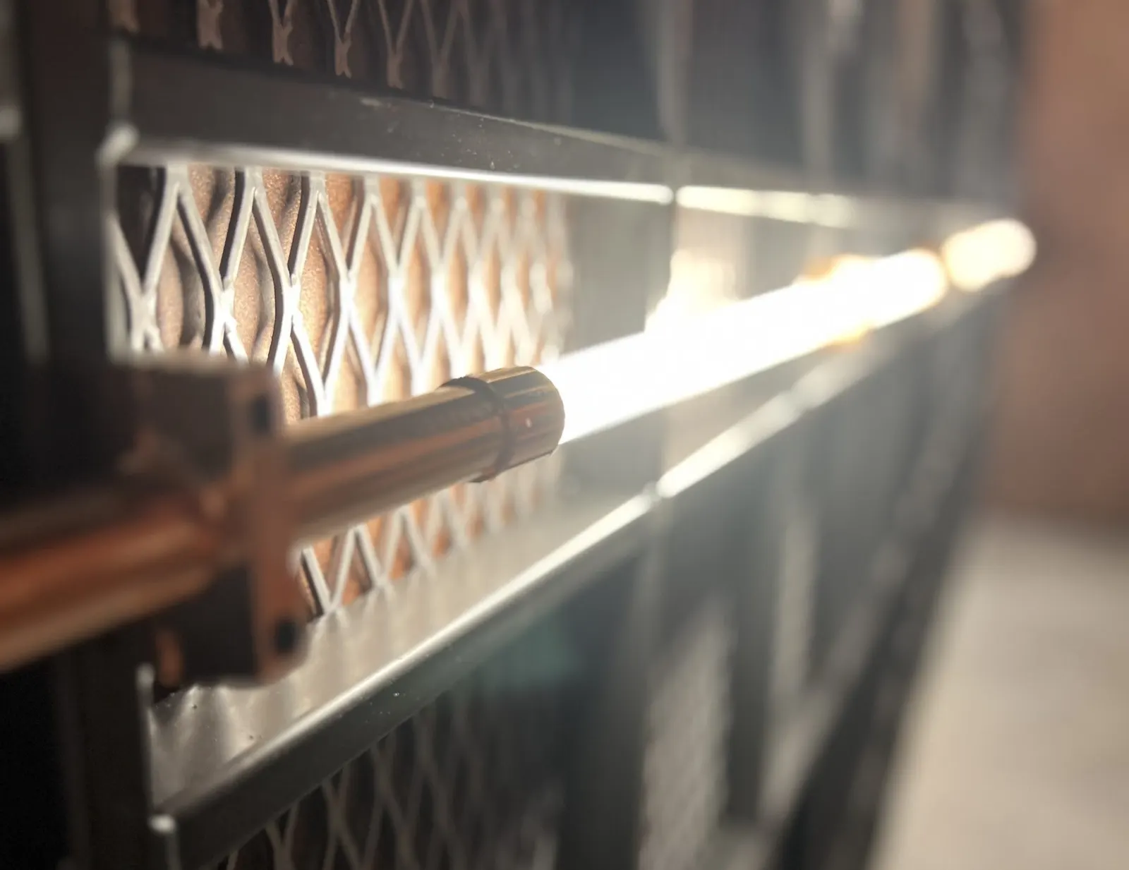 Lichtbuis met koperen houder voor een wand met ruitpatroon