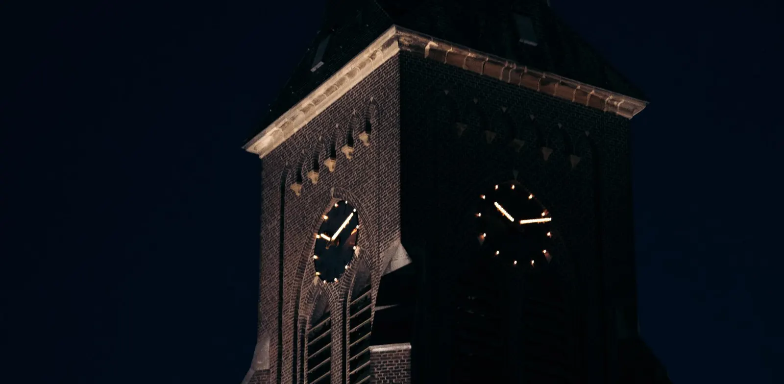 De toren van de Sint Martinuskerk in Vijlen bij nacht, de wijzerplaten verlicht