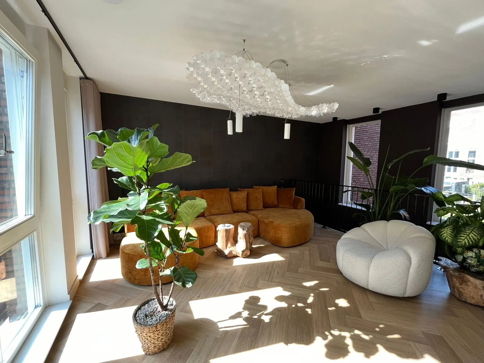 Zithoek met lichtobject aan het plafond en zonlicht door hoge ramen