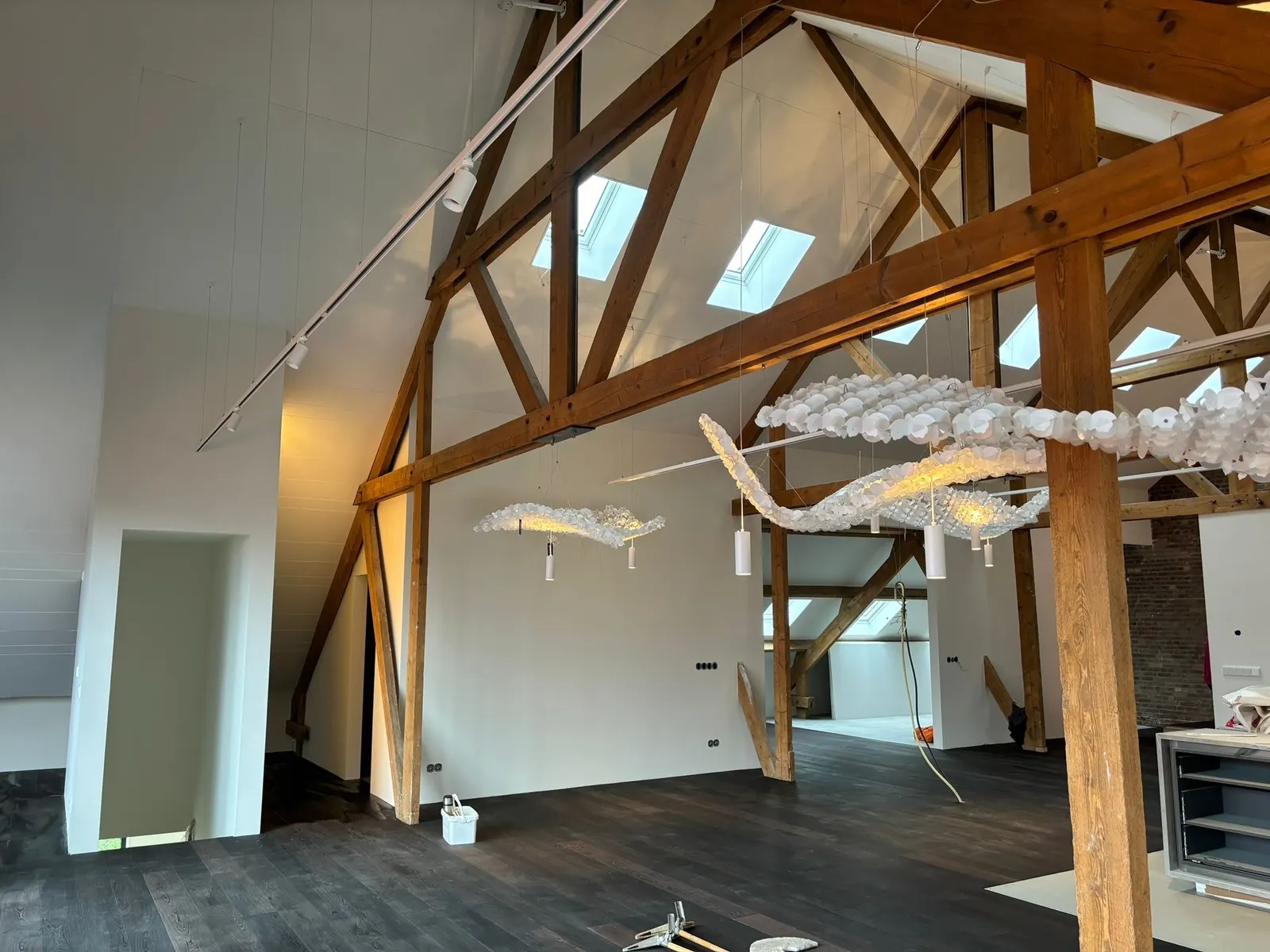 Zolder met houten spanten, dakramen en zwevende lichtobjecten