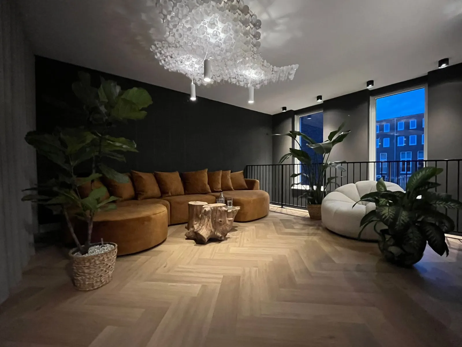 Lounge met donkere wanden, een kristallen lichtobject en warme spots