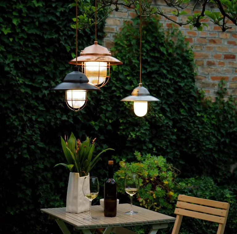 Genuit-hanglampen buiten boven een tafel tussen het groen