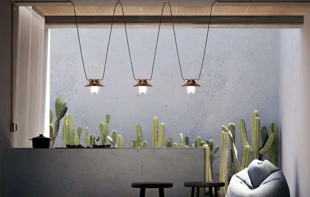 Drie koperen Genuit-hanglampen boven een rij cactussen